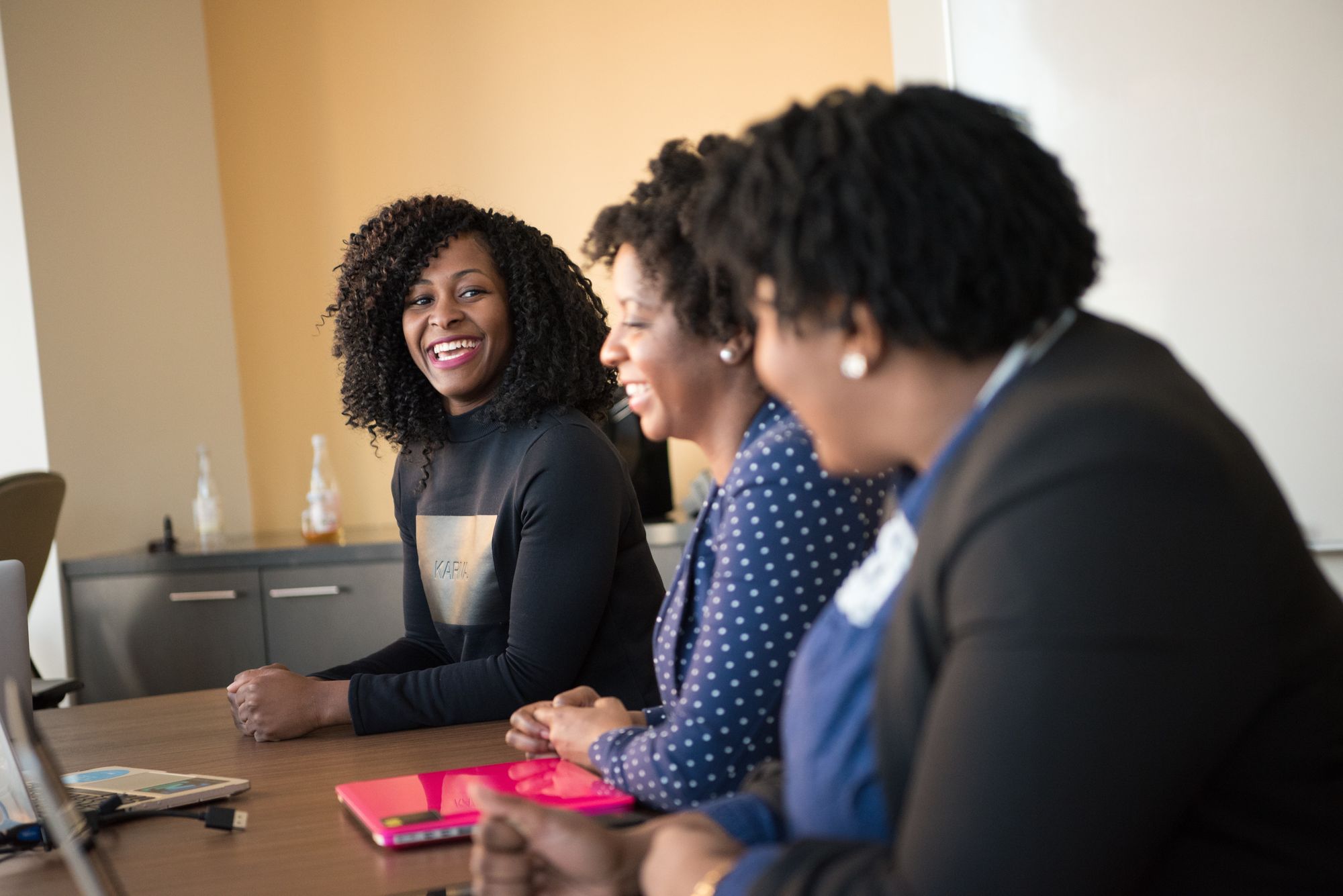 three women sit at a conference table